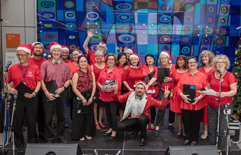 A staff choir in Santa hats performing in the hospital atrium